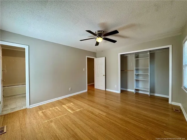 a view of empty room with wooden floor and fan