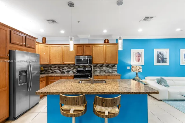 a kitchen with stainless steel appliances granite countertop a sink and a refrigerator