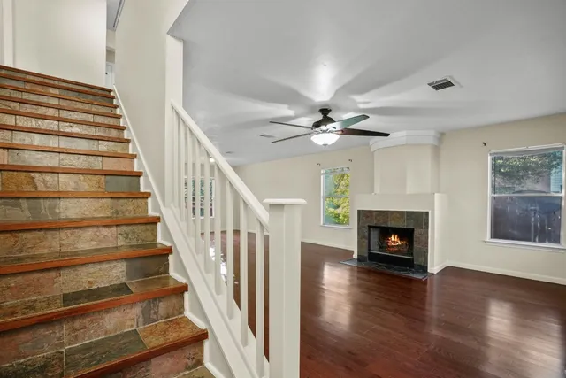 a view of an empty room with wooden floor fireplace and a window