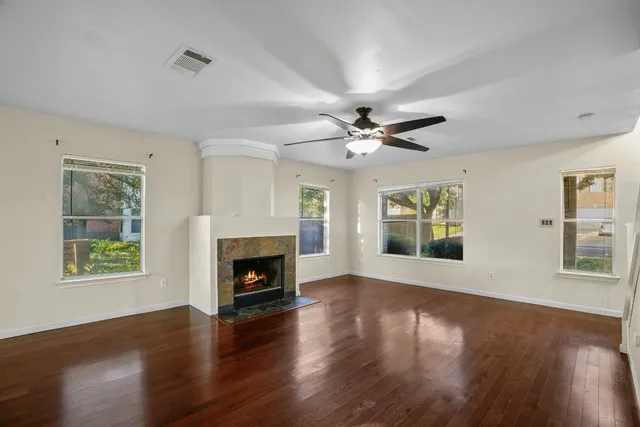 a view of an empty room with wooden floor fireplace and a window