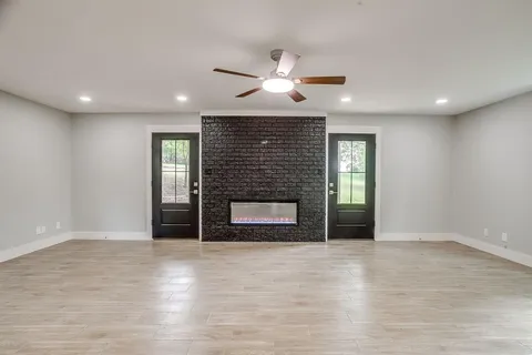 an empty room with wooden floor fireplace and windows