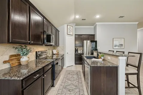 a large kitchen with granite countertop lots of counter space and stainless steel appliances