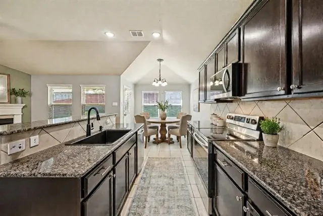 a large kitchen with granite countertop lots of counter space and stainless steel appliances