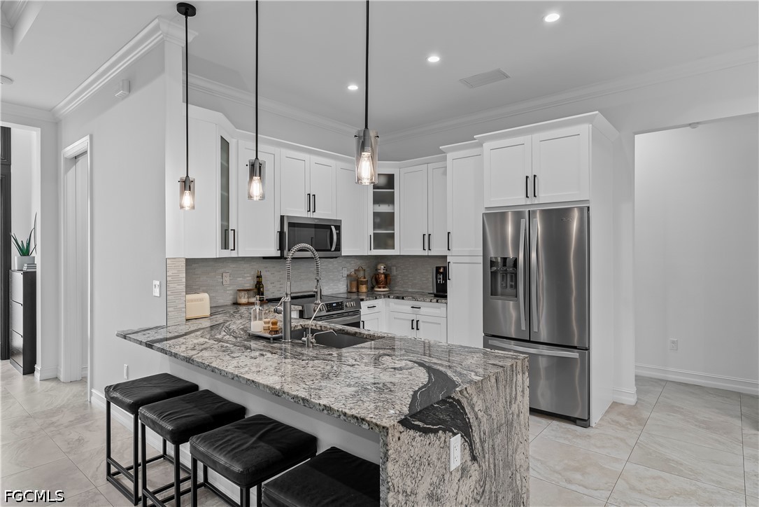 4498 8th Street Northeast Naples, FL 34120 - Photo 10 of 49 a kitchen with stainless steel appliances granite countertop a refrigerator a stove a sink a dining table and chairs