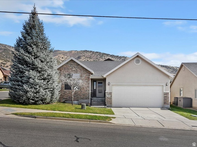 818 Mahogany Ridge Road Morgan, UT 84050 - Photo 1 of 1 View of front facade with driveway, stone siding, stucco siding, an attached garage, and a residential view