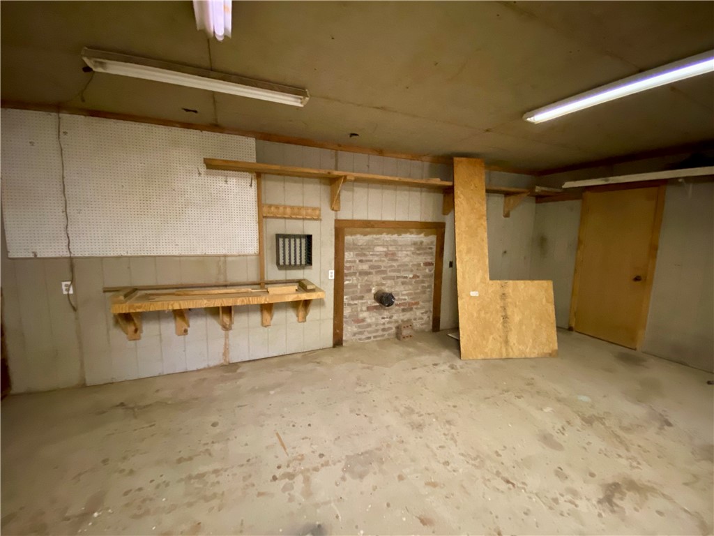 648 Dequeen Lake Road De Queen, AR 71832 - Photo 44 of 46 This area features a concrete floor, fluorescent lighting, and a built-in workbench with pegboard backing