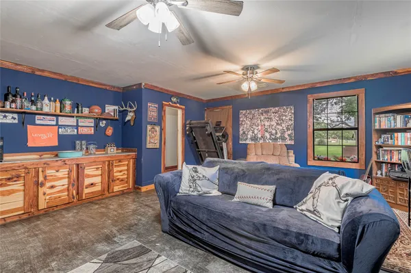 a living room with furniture a ceiling fan a rug and a bookshelf