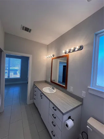 a bathroom with a granite countertop sink a mirror and a toilet