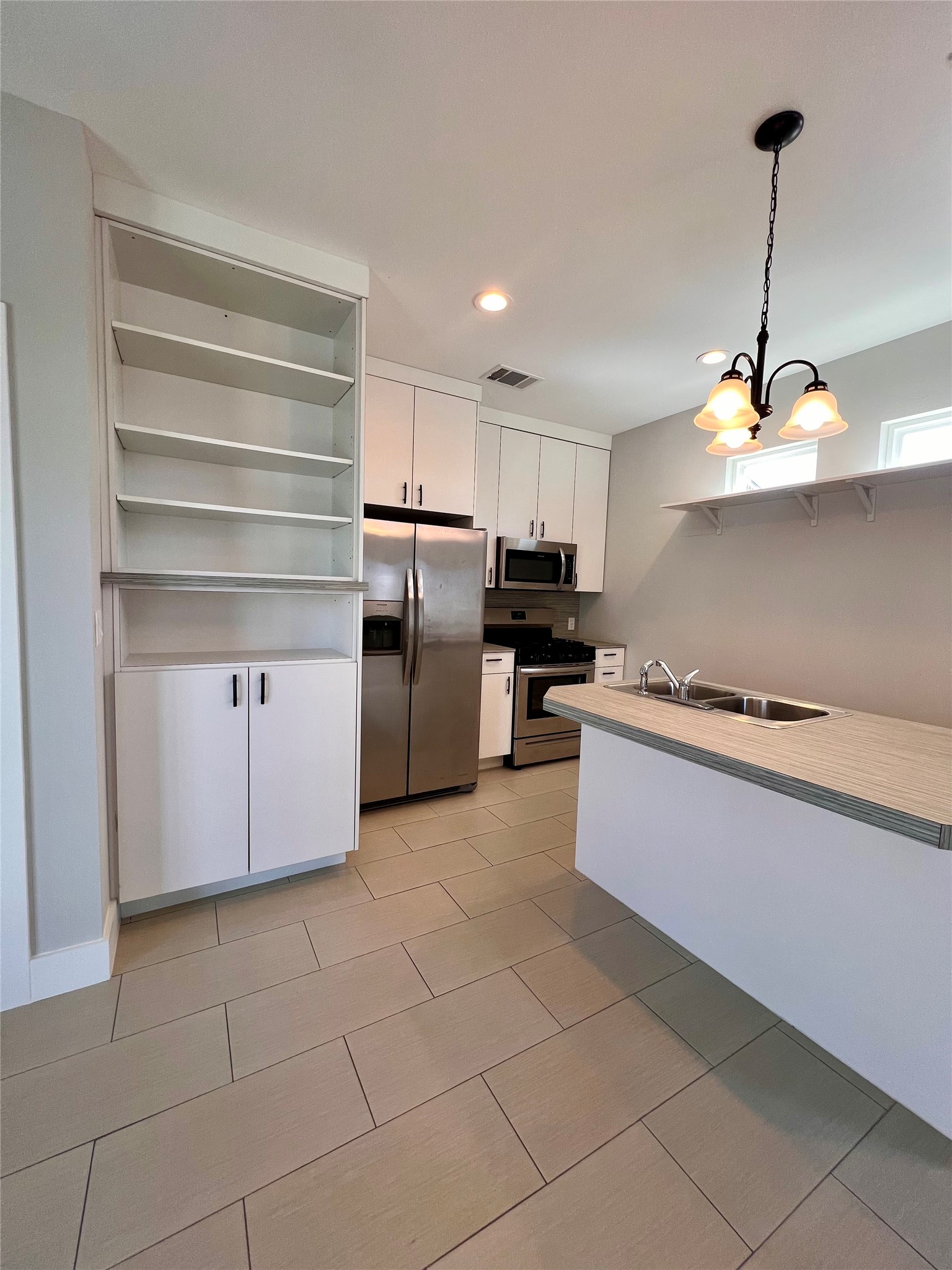1101 Stobaugh Street, Unit B Austin, TX 78757 - Photo 19 of 21 a kitchen with kitchen island granite countertop a stove a sink and a refrigerator