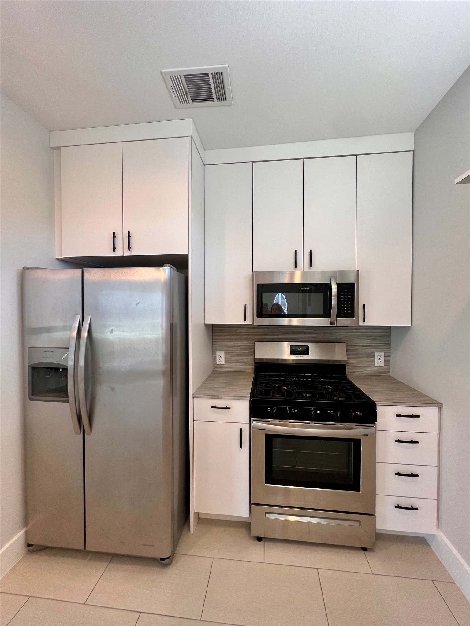 1101 Stobaugh Street, Unit B Austin, TX 78757 - Photo 20 of 21 a kitchen with white cabinets and stainless steel appliances