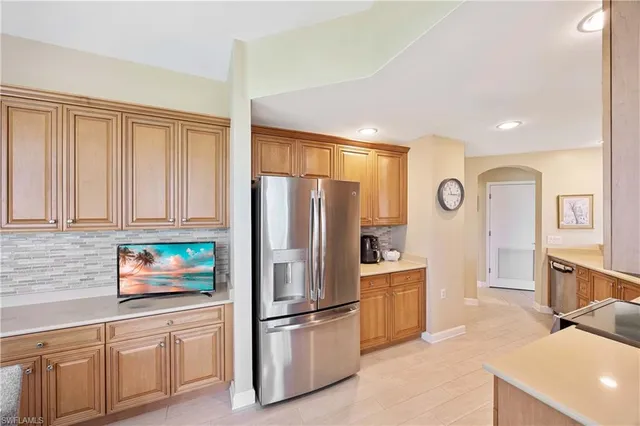 a kitchen with stainless steel appliances a dining table chairs and a refrigerator