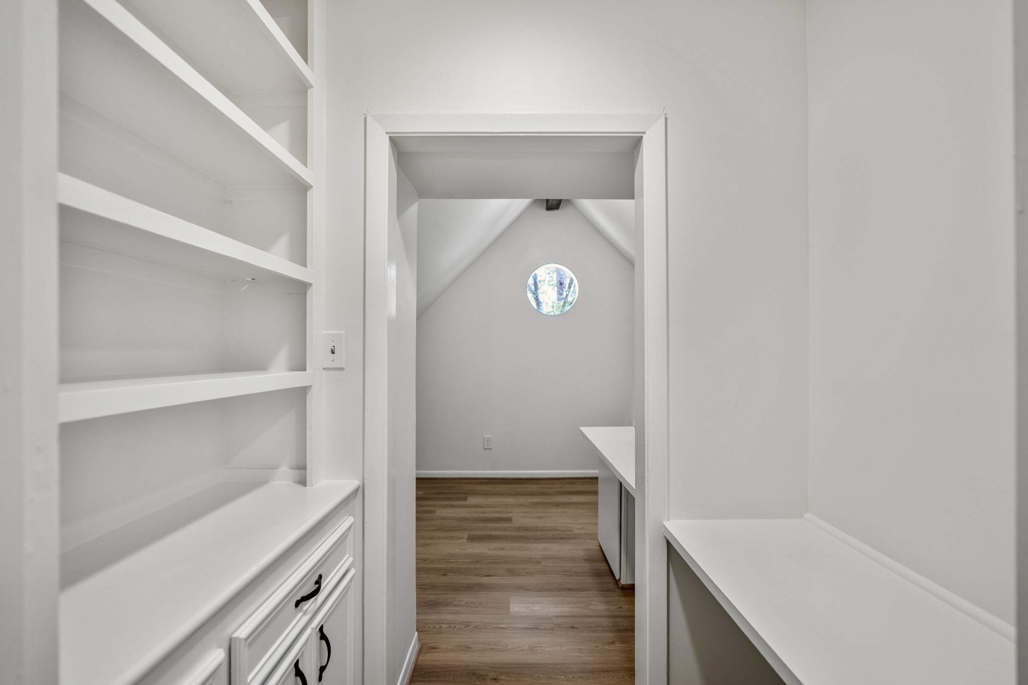 6303 Larkmount Drive Spring, TX 77389 - Photo 35 of 50 Entering the bonus room feels like a fun little surprise, with a built-in transition space that almost feels like a tucked-away passage leading you in. Open shelving, cabinet storage, and a desk-style surface create a smart landing spot before the room opens up just beyond.