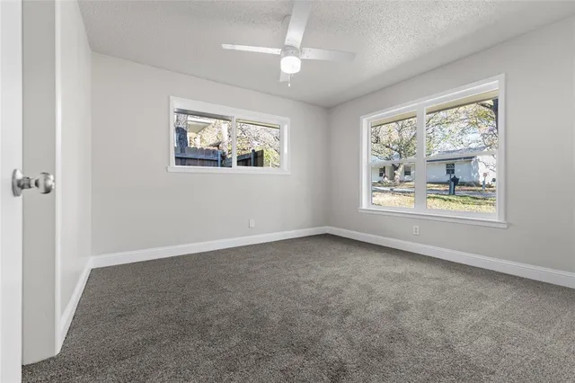an empty room with windows and ceiling fan