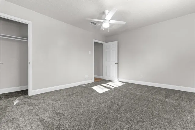 an empty room with a ceiling fan and a window