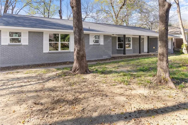 a view of a house with backyard and trees