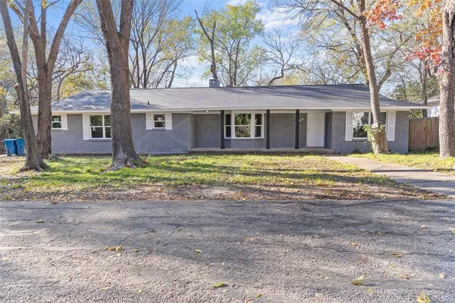 a view of a house with a big yard and large tree