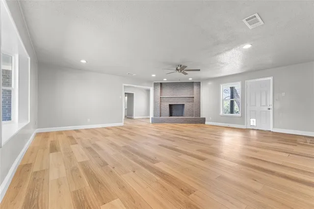a view of empty room with wooden floor and fireplace