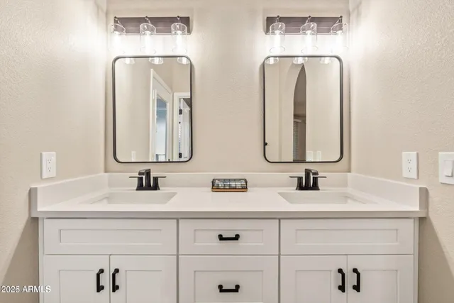 a bathroom with double vanity sinks and two mirror