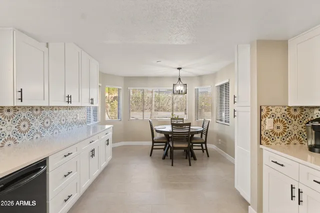 a large white kitchen with granite countertop a sink and a large window