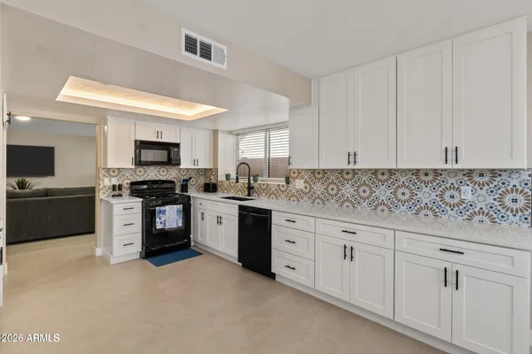 a kitchen with granite countertop white cabinets and stainless steel appliances