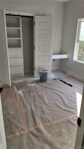 a view of an empty room with cabinet and a window
