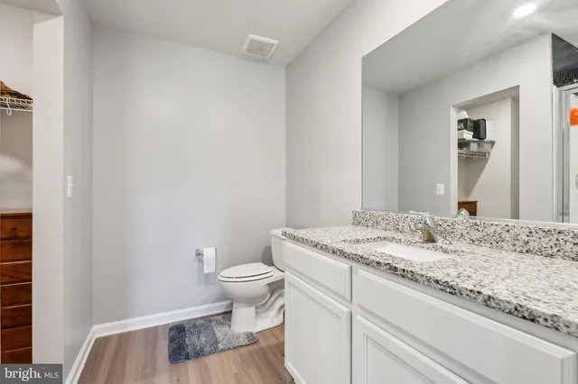 a bathroom with a granite countertop sink a toilet and a mirror
