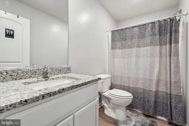 a bathroom with a granite countertop sink a toilet and a mirror