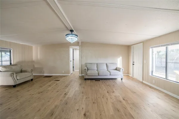 a view of an empty room with wooden floor and window