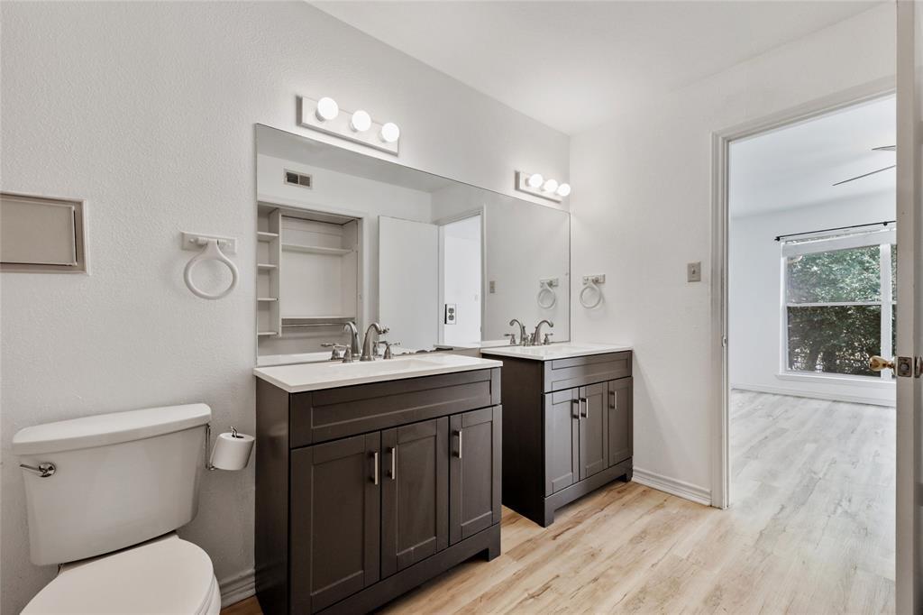 2450 Wickersham Lane, Unit 106 Austin, TX 78741 - Photo 6 of 13 a spacious bathroom with a granite countertop toilet a sink and a mirror