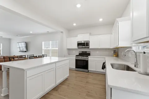 a kitchen with stainless steel appliances white cabinets a sink a stove a refrigerator and white cabinets