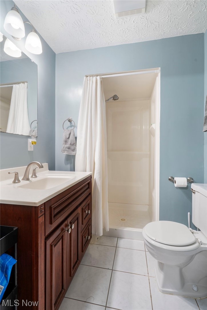 801 Netherwood Avenue Northwest Canton, OH 44708 - Photo 27 of 44 Bathroom with toilet, curtained shower, vanity with extensive cabinet space, tile flooring, and a textured ceiling