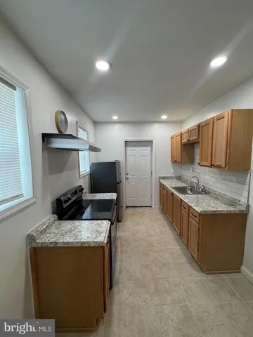 a kitchen with granite countertop sink and refrigerator