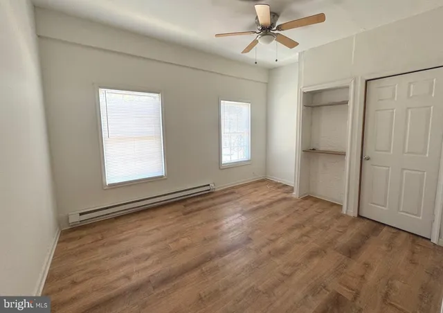 a view of empty room with wooden floor and ceiling fan