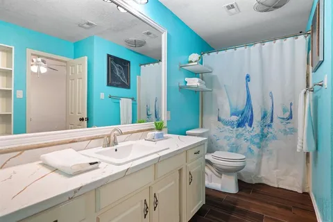 an empty room with wooden floor chandelier fan and windows