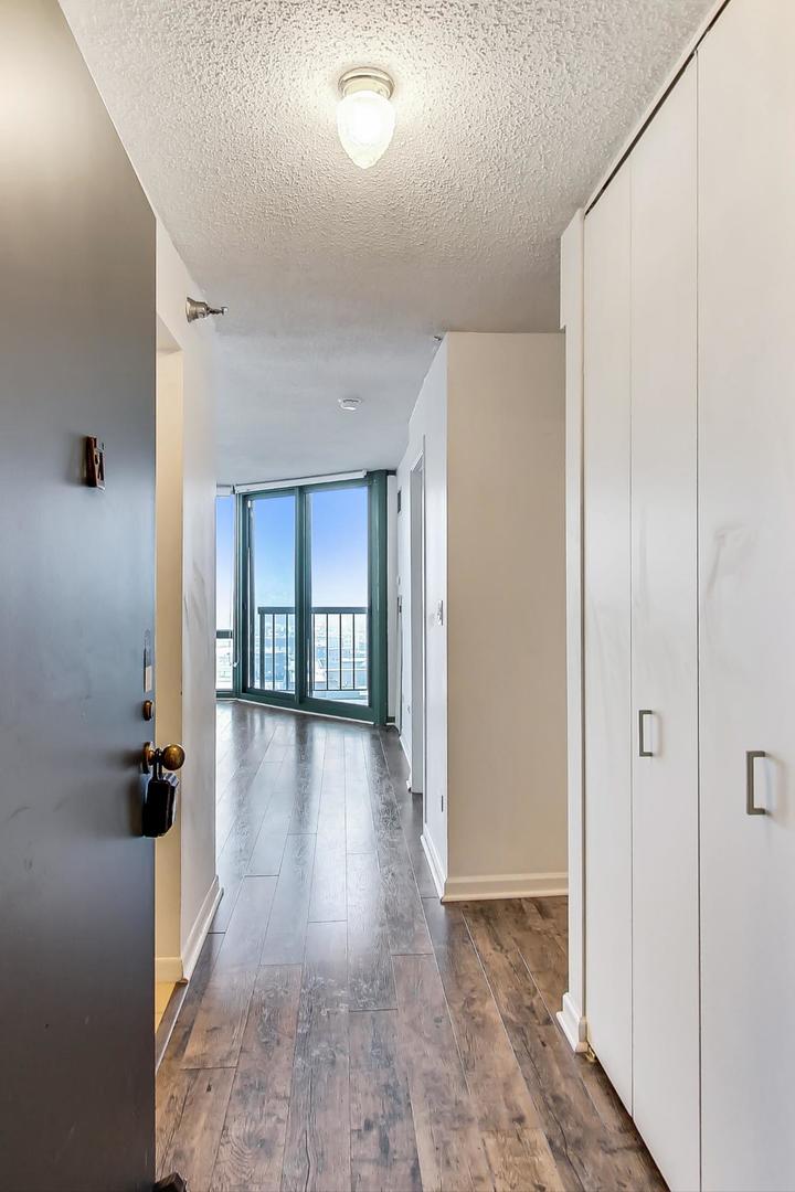 111 West Maple Street, Unit 1410 Chicago, IL 60610 - Photo 16 of 41 a view of a hallway to a livingroom with wooden floor and windows