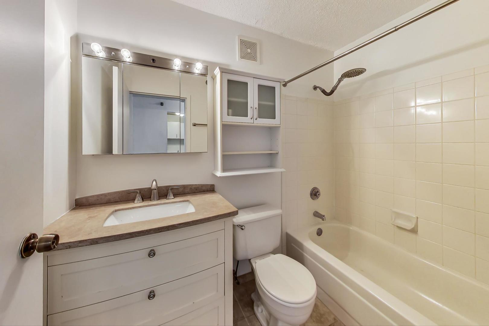 111 West Maple Street, Unit 1410 Chicago, IL 60610 - Photo 30 of 41 a bathroom with a granite countertop sink toilet vanity mirror bathtub and shower