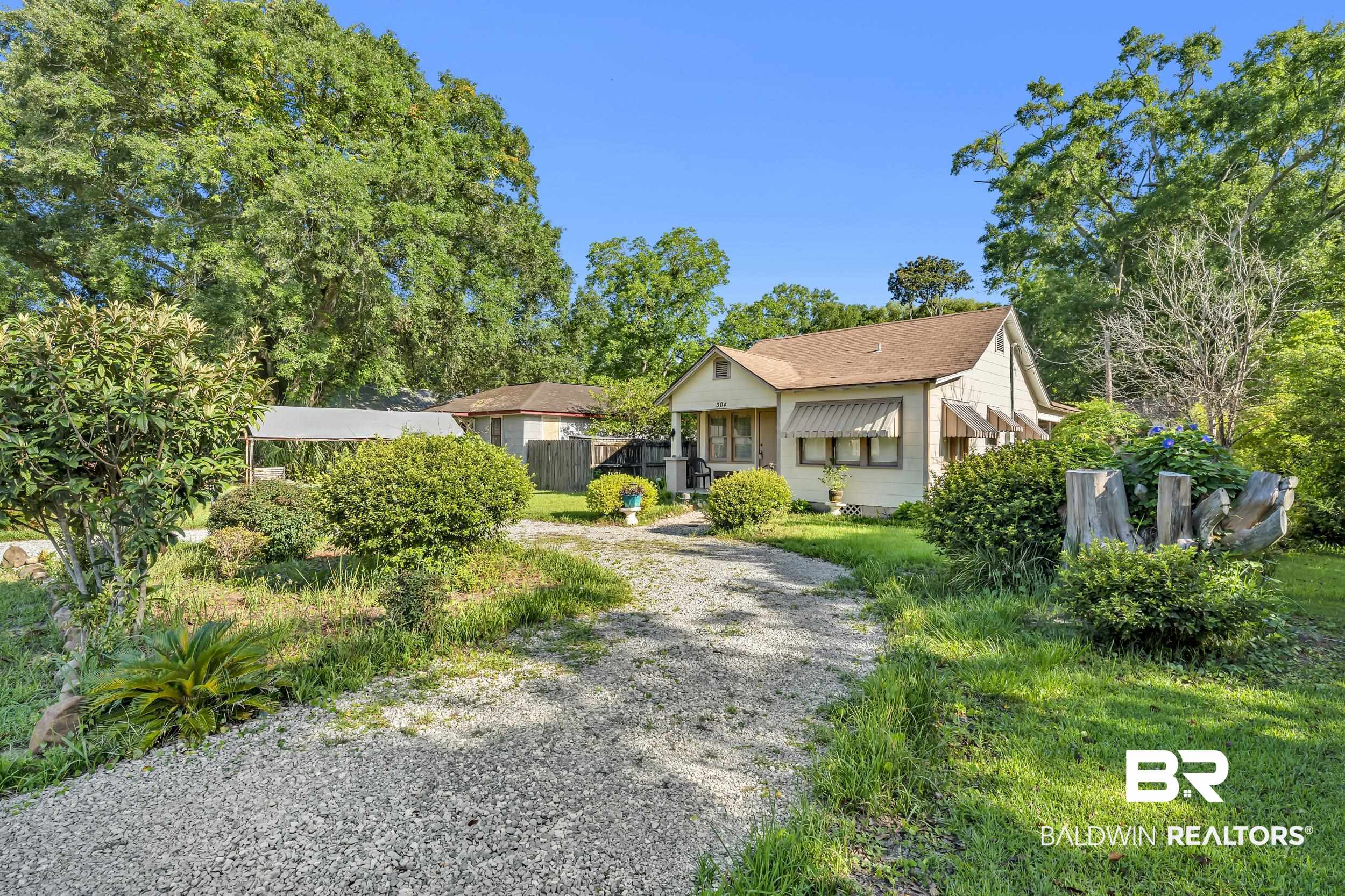 304 West Myrtle Avenue Foley, AL 36535 - Photo 29 of 29 Single-story residence featuring a gravel driveway, mature trees, and established shrubs