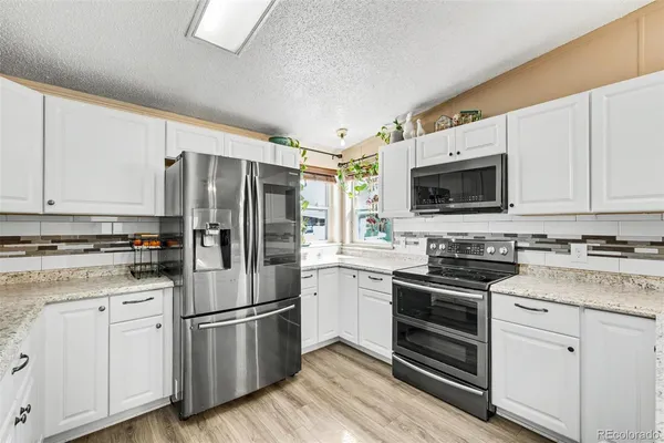 a kitchen with cabinets stainless steel appliances and wooden floor