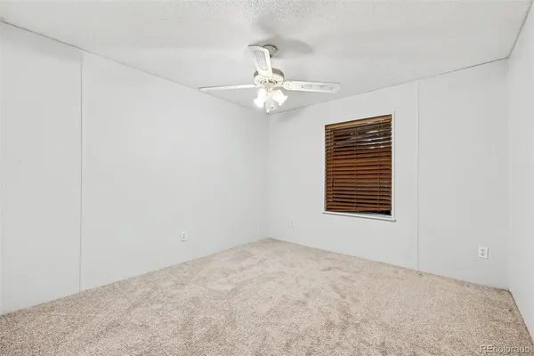 an empty room with a window and ceiling fan