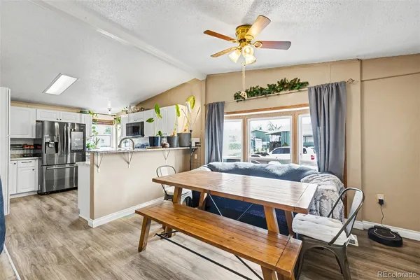 a living room with stainless steel appliances furniture a rug and a kitchen view