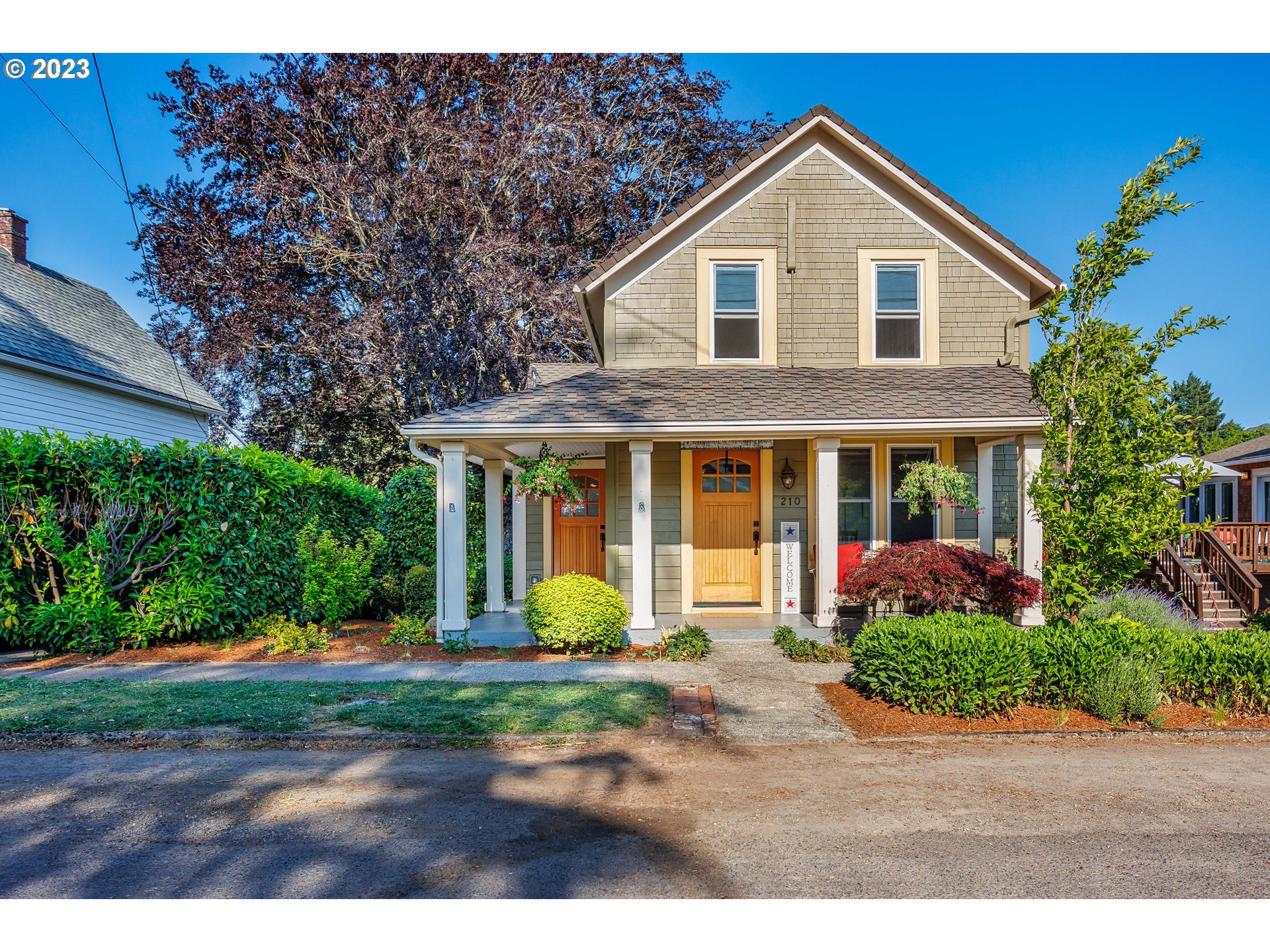 a front view of a house with a yard and potted plants