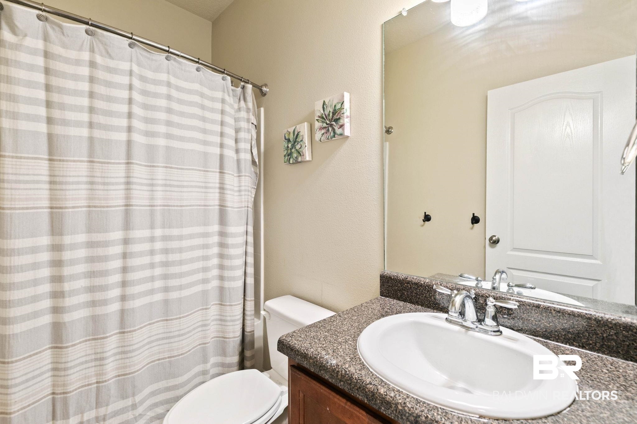 2216 Livingstone Court Mobile, AL 36695 - Photo 34 of 62 Bathroom featuring a vanity with a dark speckled countertop, an undermount sink with chrome fixtures, and a large wall-mounted mirror