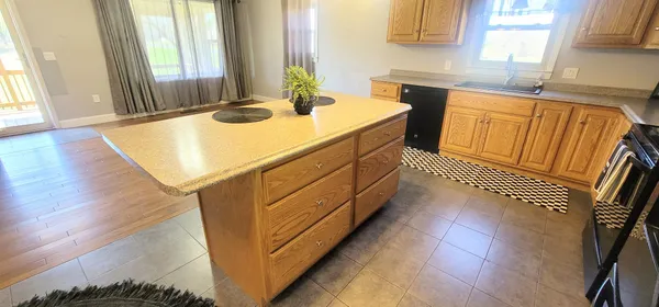 a kitchen with stainless steel appliances kitchen island granite countertop a sink a stove a dining table and chairs