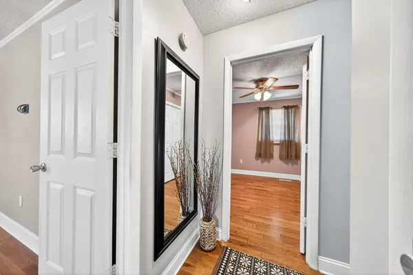 an empty room with wooden floor chandelier fan and windows