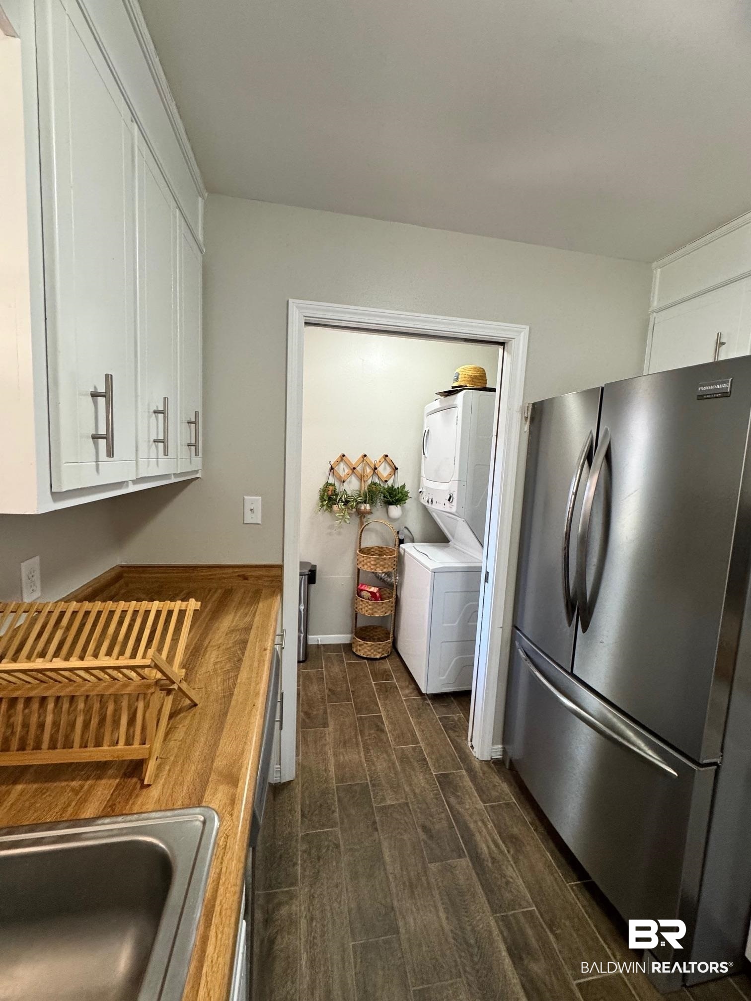 1434 Ridgewood Drive Lillian, AL 36549 - Photo 10 of 45 Kitchen with stacked washer and clothes dryer, wooden counters, sink, stainless steel fridge, and white cabinetry