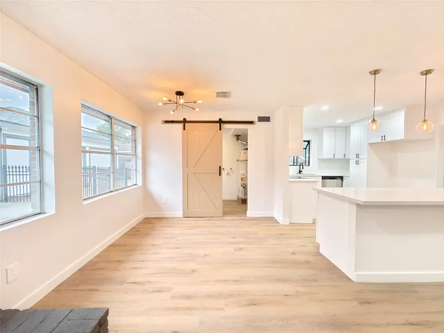 a large white kitchen with cabinets a sink and a window