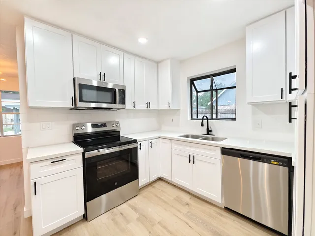 a kitchen with white cabinets appliances and sink