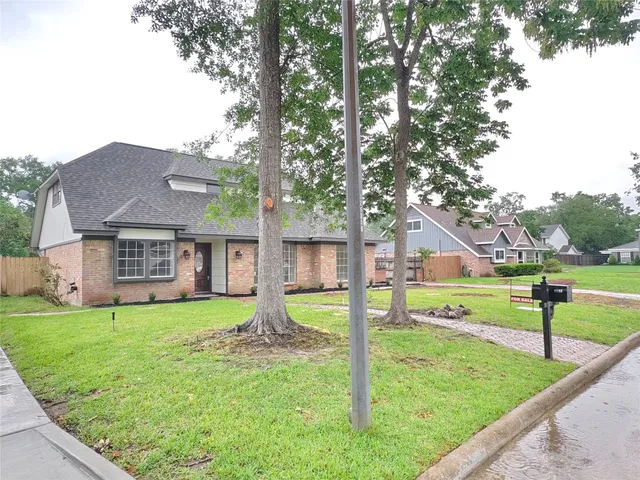 a view of a house with a yard and a large tree