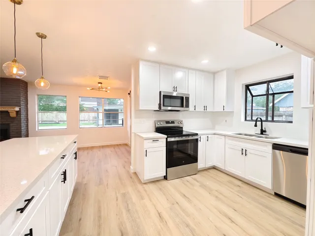 a large kitchen with granite countertop a stove top oven a sink a window and wooden floor