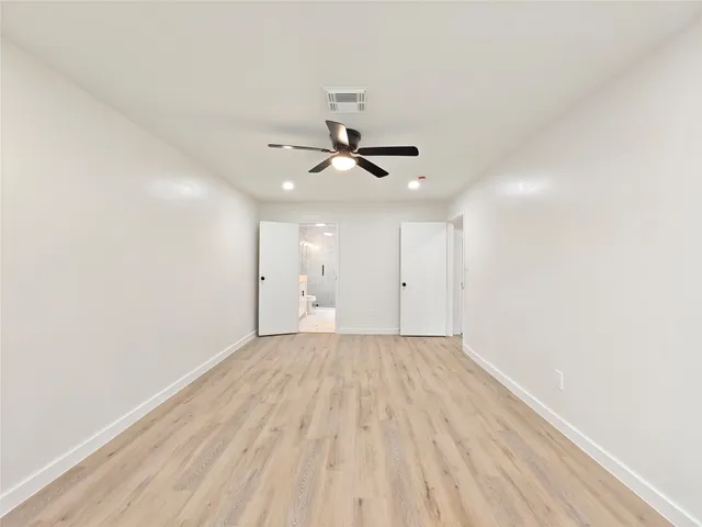 a view of empty room with wooden floor and ceiling fan